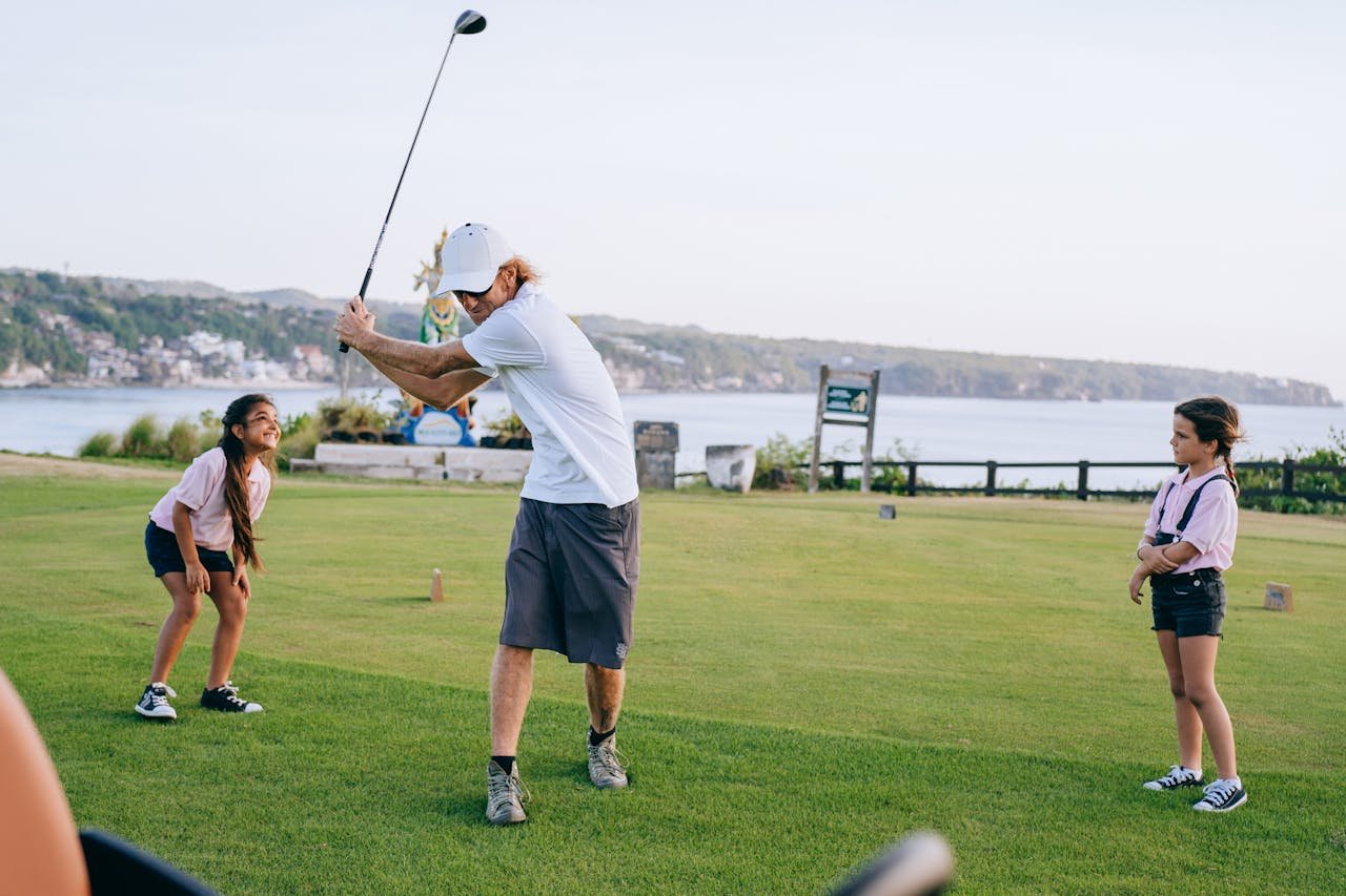 about-img-01 A family enjoying a round of golf on a picturesque outdoor course by the sea.